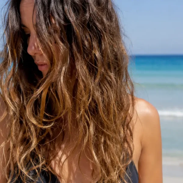 Donna con capelli secchi e disidratati dopo mare e piscina, esempio dei danni causati da sole, salsedine e cloro sui capelli