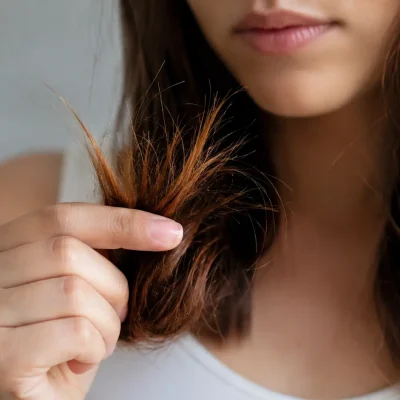 Come proteggere le punte dei capelli secchi e danneggiati: donna con capelli lunghi che osserva le punte fragili, secche e soggette a doppie punte, cura e protezione delle lunghezze, haircare cosmetico.