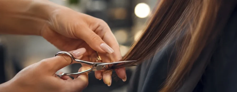 Ogni quanto tagliare i capelli: primo piano di un parrucchiere che spunta le punte di capelli lunghi e sani con forbici professionali per mantenere la chioma forte, ordinata e senza doppie punte.